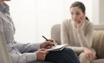 Woman sitting near another person writing notes.